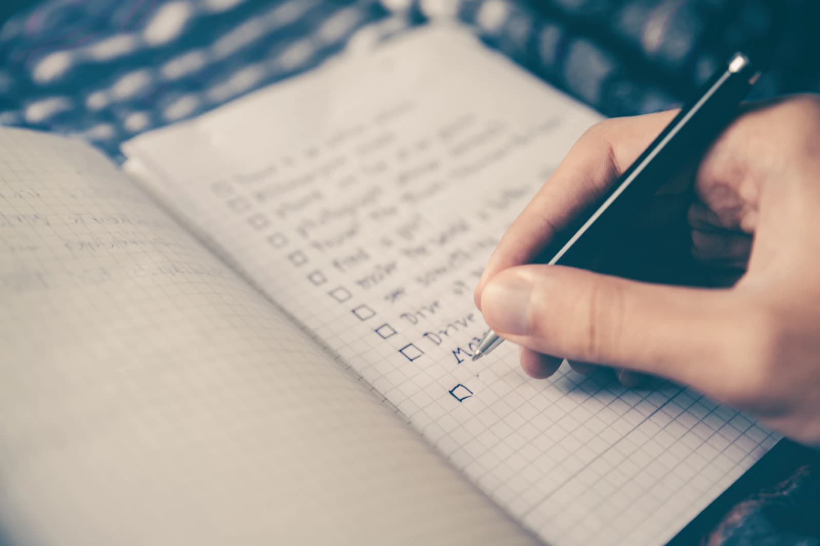 A hand writing a checklist in an open notebook